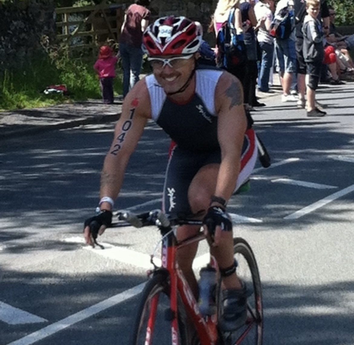 Paul on a bike, cycling at a marathon, wearing a helmet and leotard