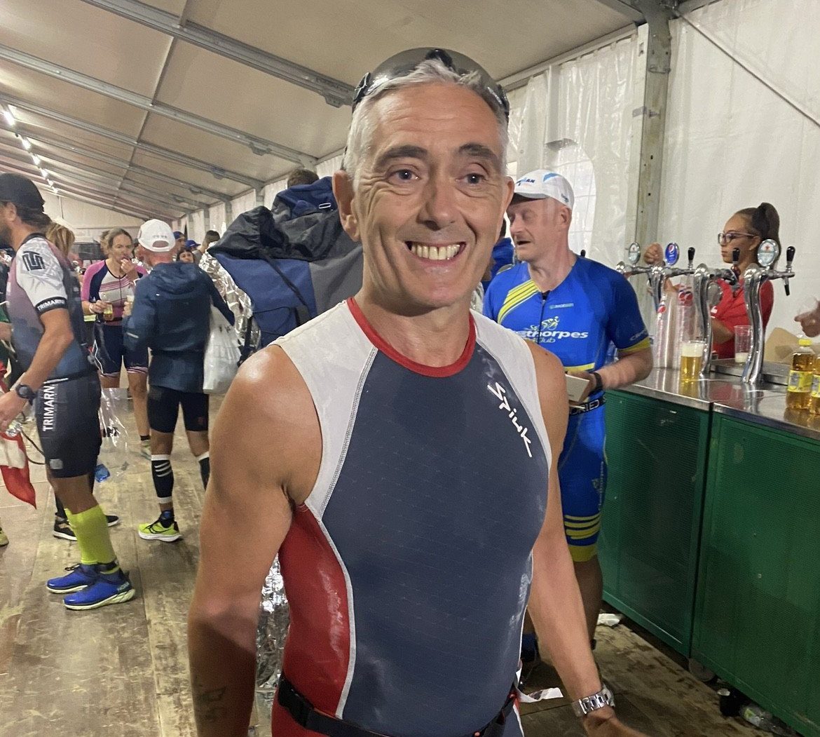 Paul after a marathon, at a bar in a marquee with all other participants, smiling